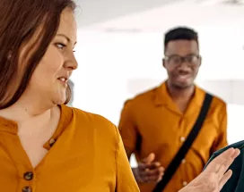 três pessoas conversando e rindo em corredor.