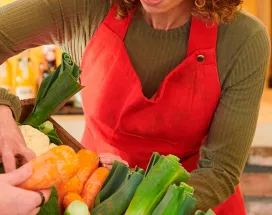 foto mostra duas pessoas mexendo em uma cesta de legumes frescos