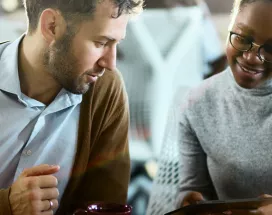 duas pessoas conversando enquanto olham algo em tablet.