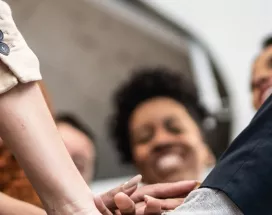 A imagem mostra um grupo de trabalhadores juntando as mãos e celebrando