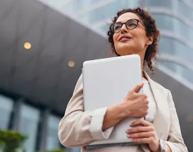 Foto mostra uma executiva em frente ao prédio em que trabalha