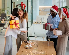 pessoas trocando presentes de natal em escritório.