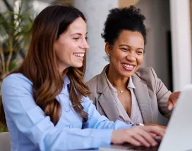 duas mulheres sorrindo para notebook.