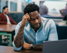 Foto mostra uma pessoa estressada no escritório