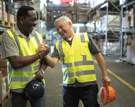 Foto mostra dois funcionários de uma empresa comemorando os resultados do final de ano
