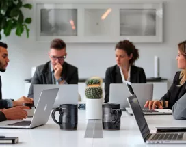 Foto mostra um grupo de pessoas trabalhando juntas para alinhar os objetivos da empresa