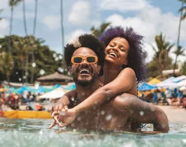 Foto mostra um casal curtindo férias na praia