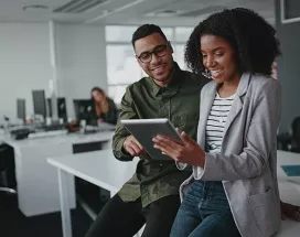 duas pessoas olhando informação em tablet no escritório.