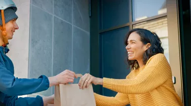 Mulher recebe delivery no local de trabalho. Ela pediu no Rappi usando o cartão Pluxee Refeição