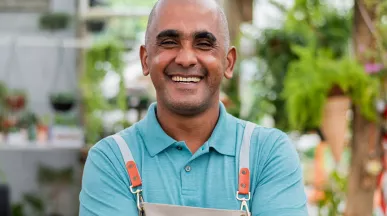 Pequeno empreendedor sorri no seu estabelecimento comercial