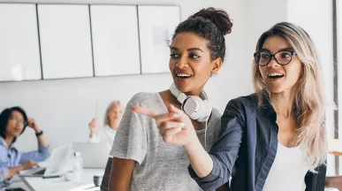 Duas colegas de trabalho conversam no escritório