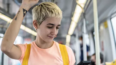 Jovem profissional vê o celular enquanto faz o caminho até o trabalho