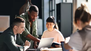Foto mostra uma equipe com pessoas de diversas origens trabalhando juntas