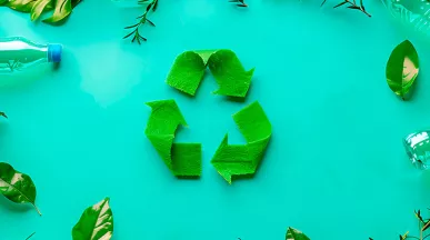 Imagem mostra um símbolo verde de reciclagem num fundo verde, com algumas garrafas de plástico vazias ao redor