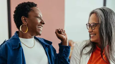 Duas colegas de trabalho conversam animadas durante o expediente