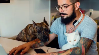 Homem trabalha de casa na companhia de seu cachorro e de seu gato