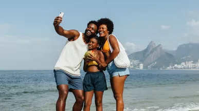 Foto mostra família (pai, mãe e filha) tirando uma selfie no Rio de Janeiro