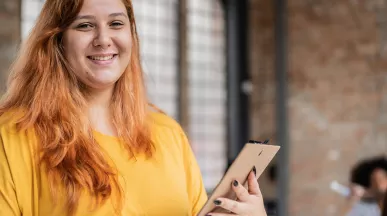 Jovem empresária sorri para a câmera segurando um tablet