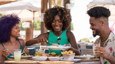 Três colegas de trabalho aproveitam o intervalo para almoçar juntos