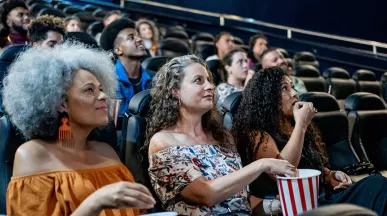 Três amigas assistem um filme brasileiro no cinema