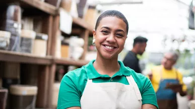 Foto mostra funcionária de uma loja de cerâmicas sorrindo para a câmera