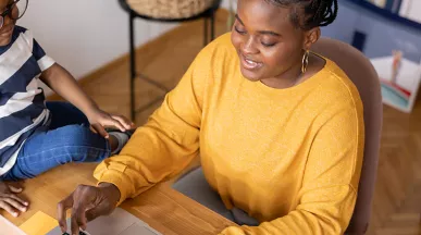 mulher trabalhando de home office com filho ao lado.