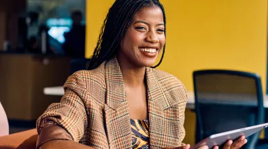 mulher sorrindo enquanto segura tablet.