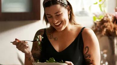 Mulher come uma salada na copa da empresa