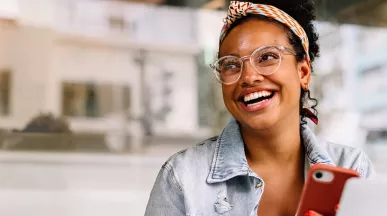 mulher sorrindo com celular na mão.