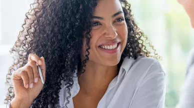 mulher sorrindo enquanto explica algo para outra.