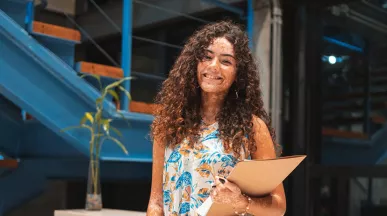 estagiária sorrindo enquanto segura documentos.