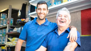 dois homens de diferentes idades sorrindo no trabalho.