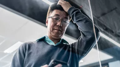 pessoa olhando o celular no trabalho com expressão de preocupação.