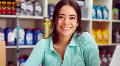 mulher sorrindo em frente a uma prateleira com itens a venda.