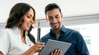 uma mulher e um homem olhando para algo em um tablet.