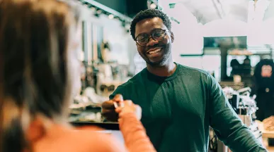 homem pagando compras enquanto sorri.