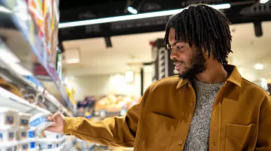 homem escolhendo itens de uma prateleira do supermercado.