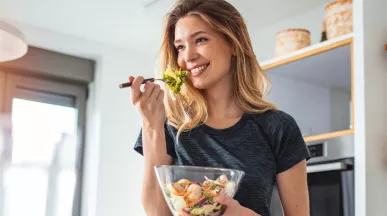 Imagem mostra uma mulher loira comendo salada