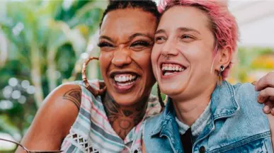 Imagem mostra duas mulheres abraçadas sorrindo e comendo felizes