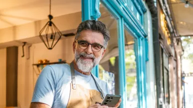 A imagem mostra um homem usando avental na frente de um estabelecimento
