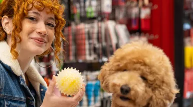 Jovem profissional compra brinquedo para seu cachorro com seu benefício flexível da empresa.