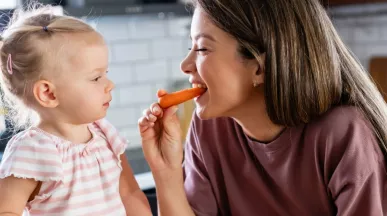 A imagem mostra uma mulher e uma criança comendo frutas