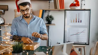 Funcionário em home office desembala um presente de Natal da empresa