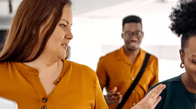 três pessoas conversando e rindo em corredor.