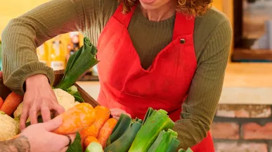 foto mostra duas pessoas mexendo em uma cesta de legumes frescos