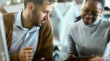 duas pessoas conversando enquanto olham algo em tablet.