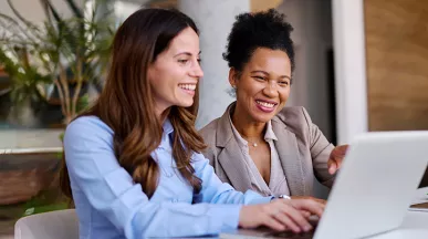 duas mulheres sorrindo para notebook.