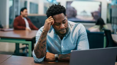 Foto mostra uma pessoa estressada no escritório