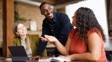 Três colegas de trabalho conversam animadamente durante uma reunião