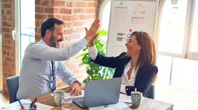 duas pessoas fazendo "toca aqui" no trabalho.